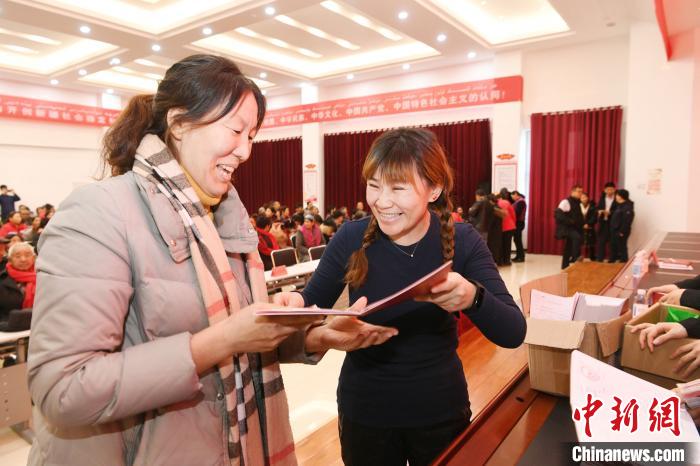 在乌尔禾区乌尔禾镇举行的股份经济合作社颁证暨分红大会上，一位(左)村民喜领股权证书和分红。　闵勇 摄