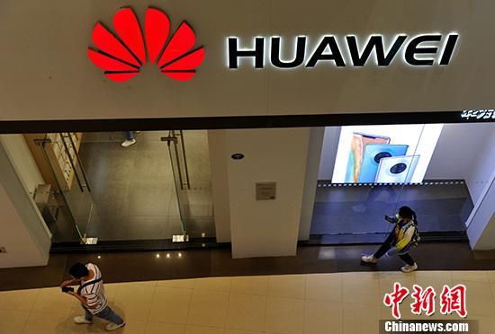 资料图：市民从华为产品专卖店旁经过。<a target=